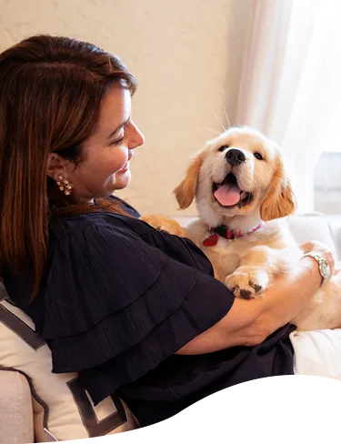 A woman on the couch holding her puppy