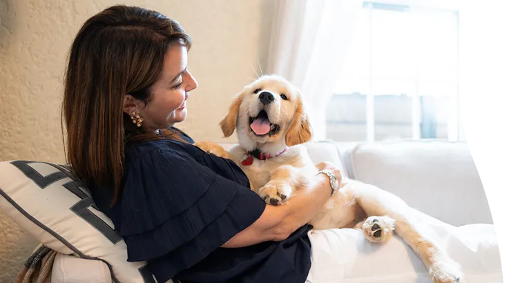A woman on the couch holding her puppy