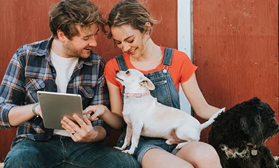Two people and a dog looking at a laptop