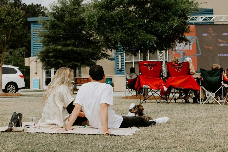 couple slitting on a blanket outdoors with dog